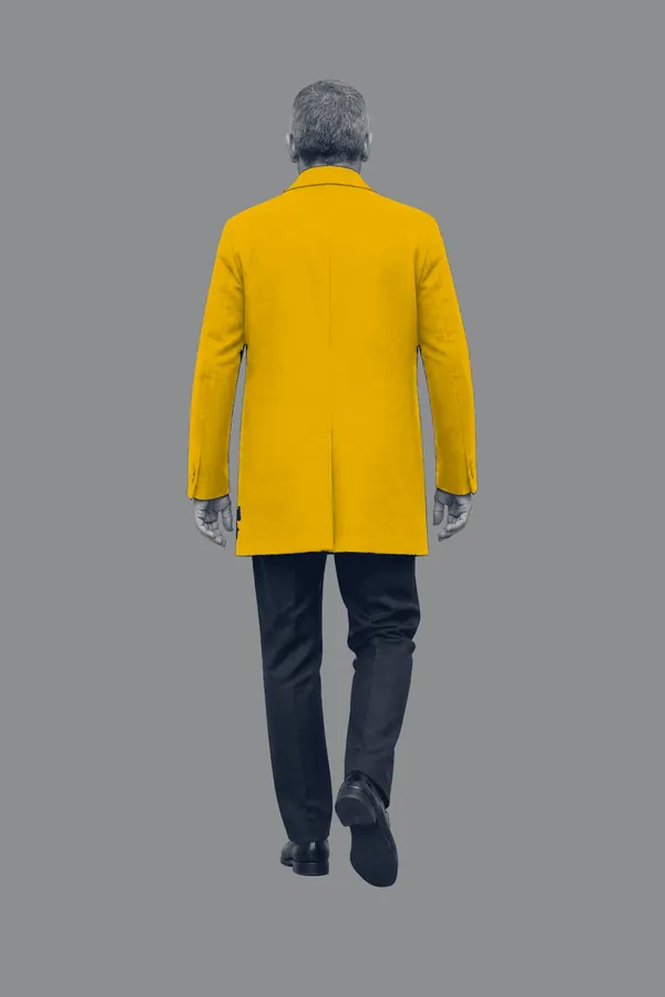 A man in an amber coat walking away, seen from behind